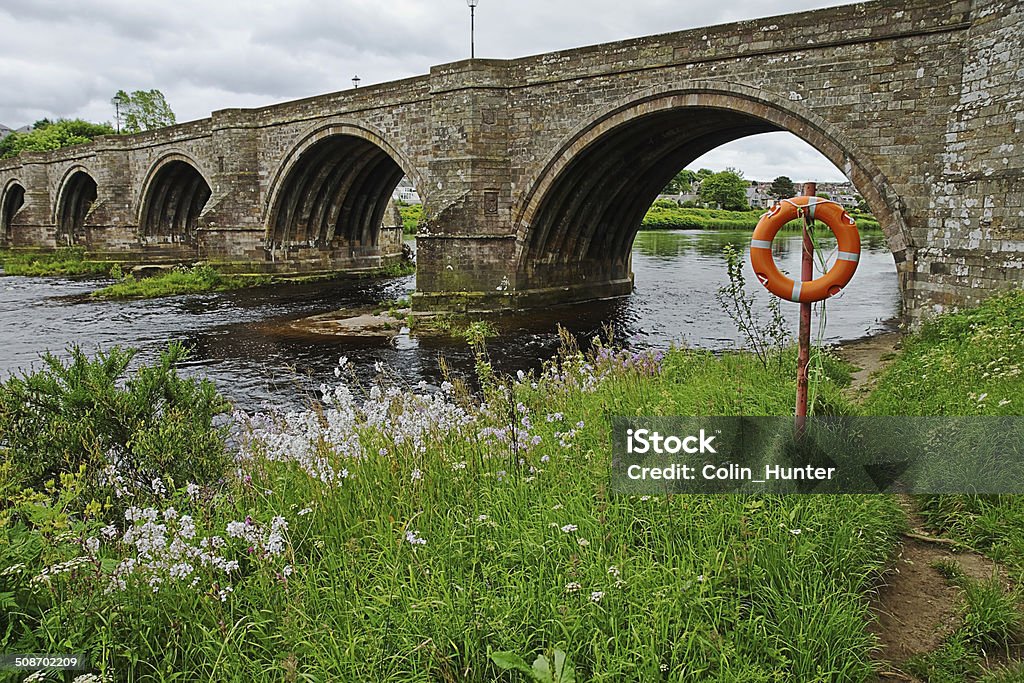 Brig of Dee and Lifebelt The Bridge of Dee in Aberdeen with some wild flowers on the river bank and a lifebelt. Life Belt Stock Photo