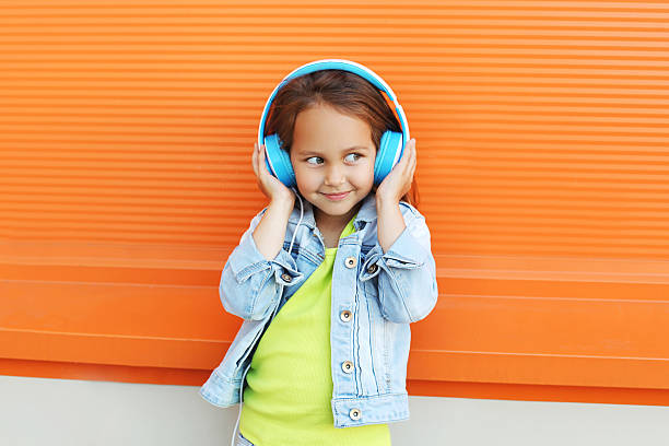 glückliches kind genießt hört musik im kopfhörer bei orange - fashion model audio stock-fotos und bilder
