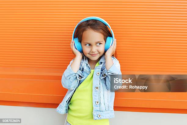 Happy Child Enjoys Listens To Music In Headphones Over Orange Stock Photo - Download Image Now