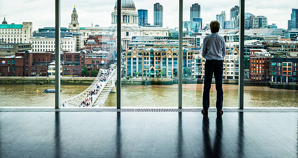 geschäftsmann blick auf die skyline von london aus seinem büro fenster - skyscraper city life urban scene building exterior stock-fotos und bilder