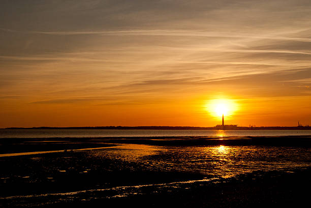 The sun setting over the Power Station at Fawley in Hampshire, seen across Southampton Water from Meon Shore near Fareham