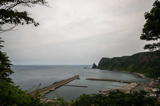 A shoreline and a small Japanese dock viewed from the top of the mountain. Taken in Shakotan peninsula, Japan.