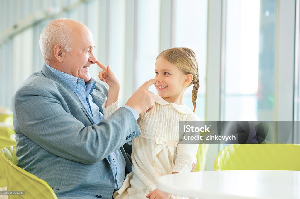 Grandfather meeting his cute granddaughter Love and happiness. Lovely granddaughter is having fun while meeting smiling happy grandfather at the cafeteria. Adult Stock Photo