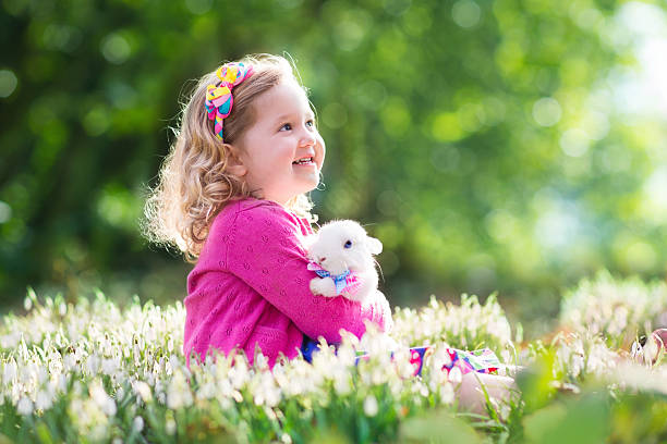 маленькая девочка играя с кролик в пасхальное яйцо хант - child easter flower little girls стоковые фото и изображения
