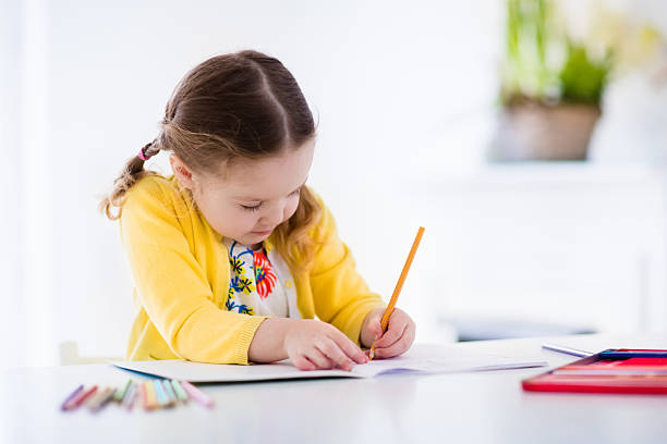 Little girl painting and writing Cute little girl doing homework, reading a book, coloring pages, writing and painting. Children paint. Kids draw. Preschooler with books at home. Preschoolers learn to write and read. Creative toddler homework preschool for babies stock pictures, royalty-free photos & images