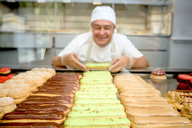 Happy Latin American man working at a pastry shop and displaying sweet cakes