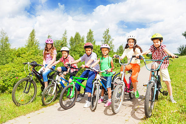 Rear view group of children on bikes and skateboard at crosswalk