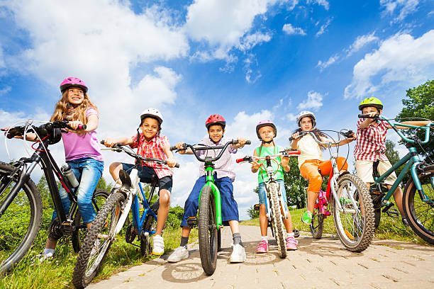 Below angle view of kids in helmets with bikes Below angle view of kids in helmets who hold their bikes and stand on path sports helmet photos stock pictures, royalty-free photos & images