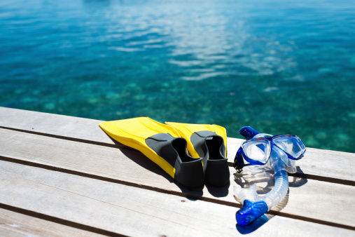 Close-up of flippers and snorkel on pier near sea.