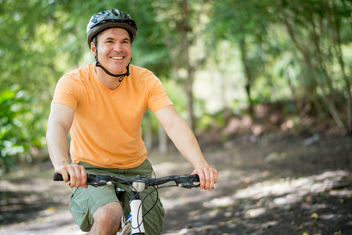 Casual man looking very happy riding a mountain bike outdoors
