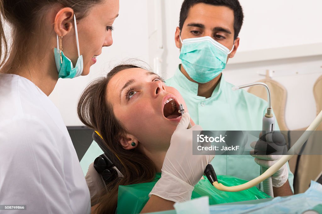 Patient is examined at dental clinic Dentist examining young girl patientâs teeth at clinic 25-29 Years Stock Photo
