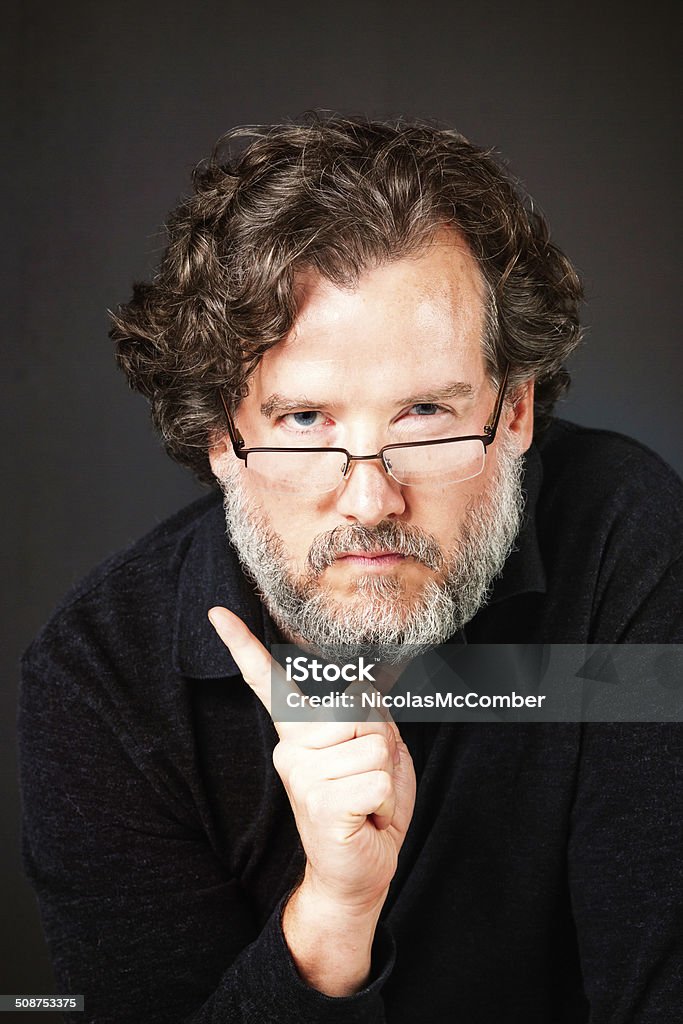 Scolding serious bearded mature man Scolding serious bearded mature man, threatening with his index finger. Studio shot against a dark gray background. 30-39 Years Stock Photo