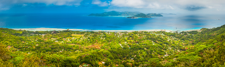 The warm turquoise waters, tropical islands and lagoons of the Seychelles overlooked by the lush rain forest jungle of the interior mountains of La Digue high above La Passe and Praslin. ProPhoto RGB profile for maximum color fidelity and gamut.