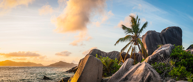 The iconic sculpted rocks and swaying palms of the Anse Source d'Argent beach beside the Indian Ocean under tropical sunset skies on the idyllic island of La Digue, Seychelles. ProPhoto RGB profile for maximum color fidelity and gamut.