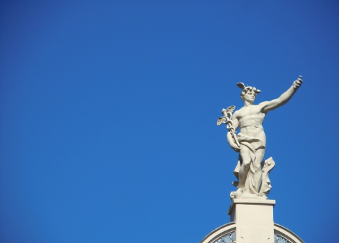 Ljubljana, Slovenia: September, 7th, 2012: A marble statue of Hermes on the top of the building against the blue sky.