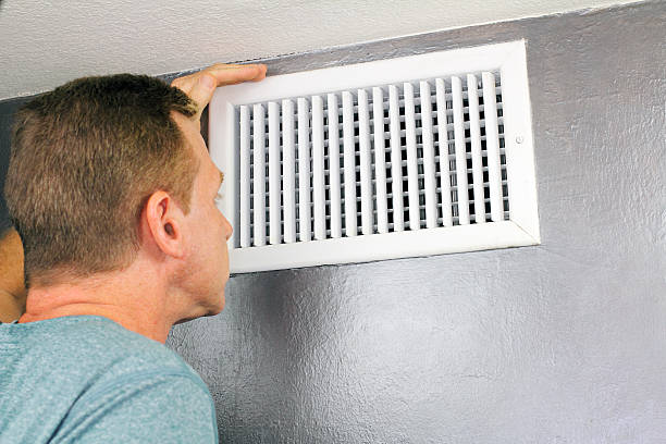 Inspecting a Home Air Vent for Maintenance Mature man examining an outflow air vent grid and duct to see if it needs cleaning. One guy looking into a home air duct to see how clean and healthy it is. air duct photos stock pictures, royalty-free photos & images
