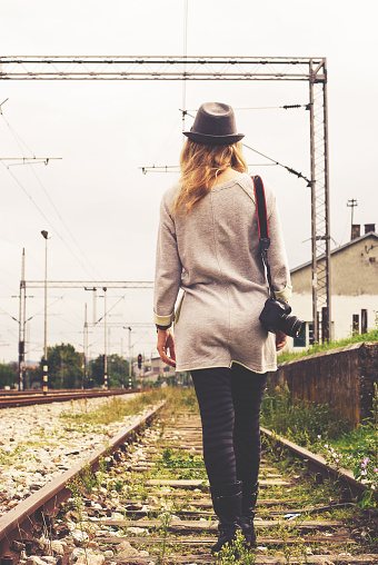 Young woman leaving the railroad, holding in his hand a camera