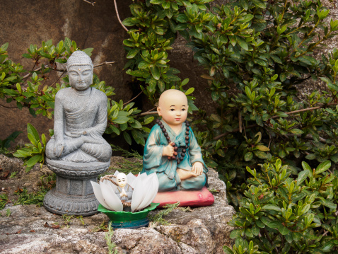 Buddhist novice monk dolls with Buddha image on the rock
