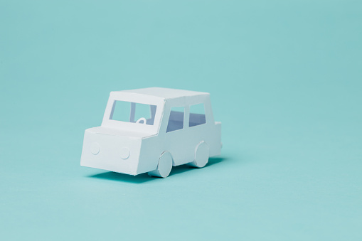 Tiny paper car on blue background.