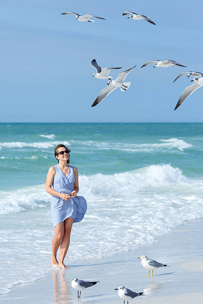 istock Young woman feeding seagulls on tropical beach, Florida 508758194