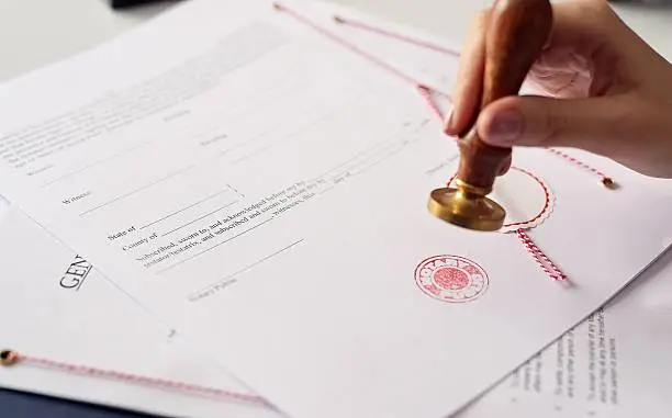 Close up on woman's notary public hand ink stamping the document. Notary public concept