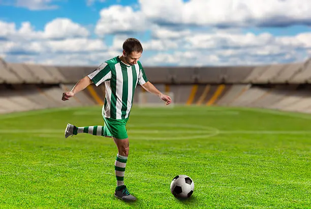 Football player kicking the ball on the football ground