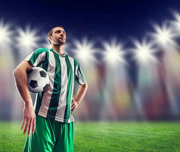 Football-player holding a ball against light