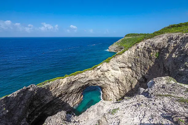 Trou au diable (Devil's hole), ancient natural arch in the cliffs of Marie Galante, turquoise caribbean sea.