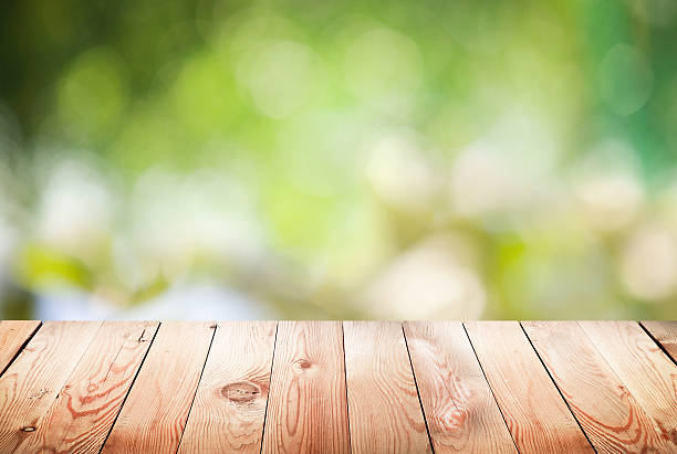 istock Empty wooden table with foliage bokeh background. 508785115