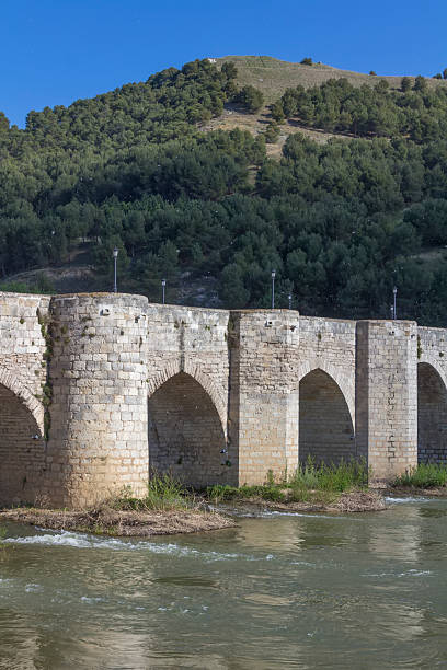 istock Old stone bridge block with arches and water 508786563