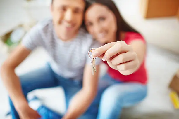 Hand of young woman holding key from new flat