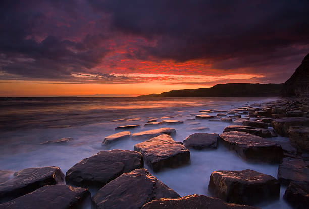 The sky clears after a rain storm just long enough to show the deep red and purple clouds over the South Dorset  jurassic coastline