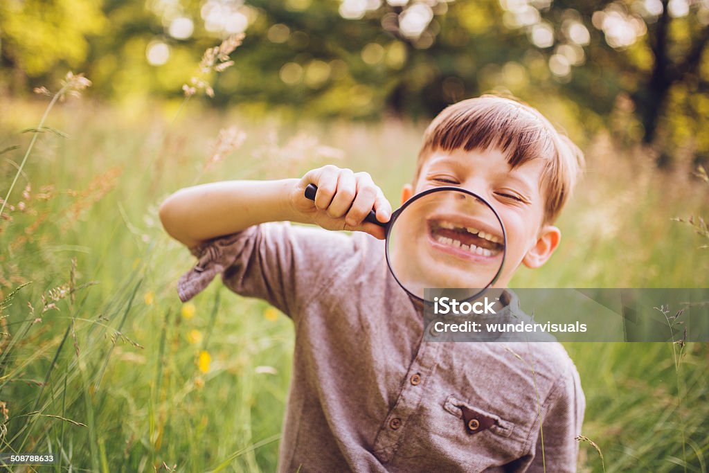 Vintage Boy with Magnifying Glass Vintage looking young boy exploring the park with magnifying glass Boys Stock Photo