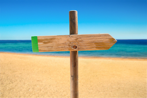 one wooden signpost in the meadow with copyspace on the beach