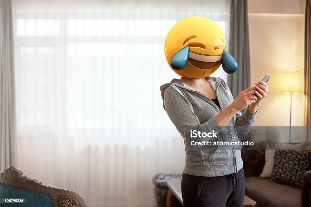 Mujer usando Emoji máscaras mientras observando a su teléfono. - Foto de stock de Emoticono libre de derechos