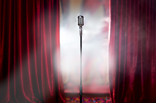 the microphone in front of red curtain on an empty stage after the concert, smoke