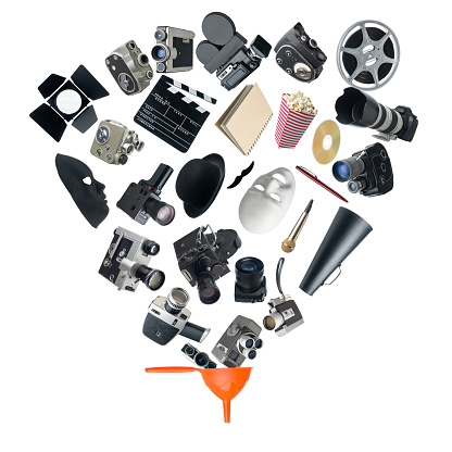 Large group of various cinema equipments and symbols falling into an orange funnel on white background.Home video cameras,dslr ,mirrorless,,film and digital cameras,theatre masks,hats, pop corn bag,dvd,microphone,pen,notebook,mustache,film slate,film reel,megaphone etc are used.All objects are falling into a funnel.Searching for best gear during shopping concept is aimed.No people are seen in frame.Shot with medium format camera Hasselblad in studio then combined with software.