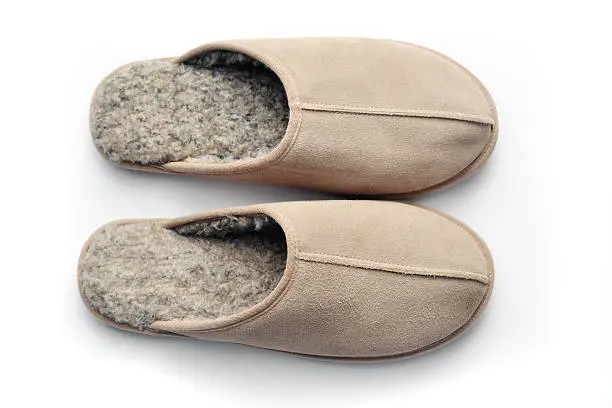 Closeup of a pair of men's slippers on a white background with shadows from above.  