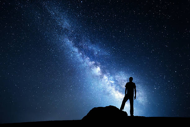 млечный путь. ночное небо и силуэт стоя человек - rock human hand human arm climbing стоковые фото и изображения
