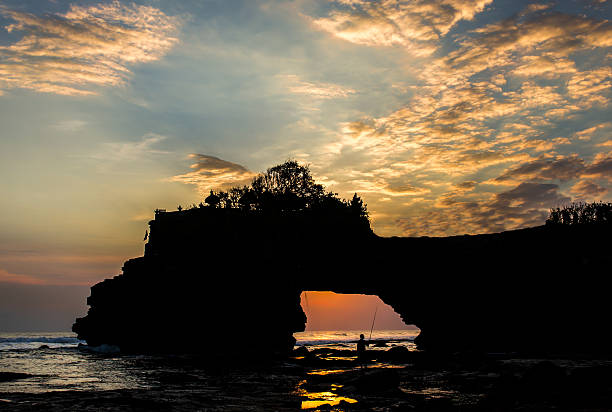 Fishing at Sunset A man fishing at sunset at Tanah Lot, Bali. The sunset here is really incredible. tanah lot sunset stock pictures, royalty-free photos & images