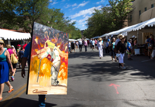 Santa Fe, USA - August 24, 2014: Mateo Romero, a Cochiti Pueblo painter, carries one of his paintings toward his booth at at the 2014 annual Santa Fe Indian Market.