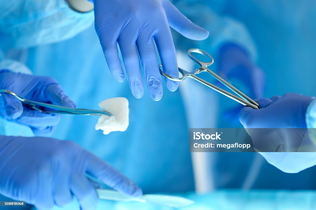 Surgeons hands holding and passing surgical instrument to other Surgeons hands holding and passing surgical instrument to other doctor while operating patient. Resuscitation medicine team holding steel medical tools saving patient. Surgery and emergency concept Work Tool Stock Photo