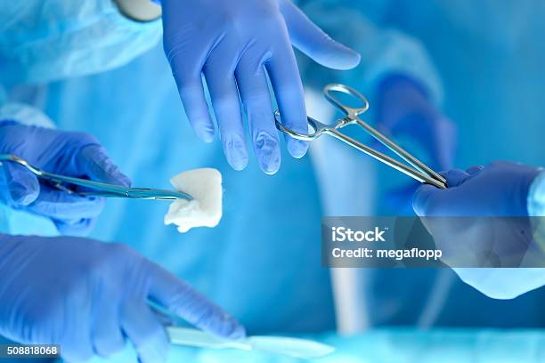 Surgeons Hands Holding And Passing Surgical Instrument To Other Stock Photo - Download Image Now