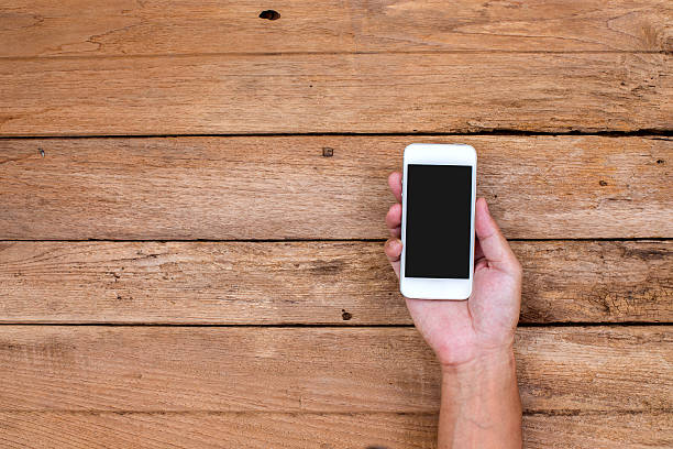 istock Man hand holding smart phone on wood background 508818377