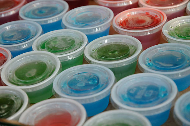 Jello Shots. Jello shots in plastic cups with lids on.  Served at parties and bars as a fun food, typically containing liquor such as vodka,tequila or whiskey. gelatin dessert stock pictures, royalty-free photos & images