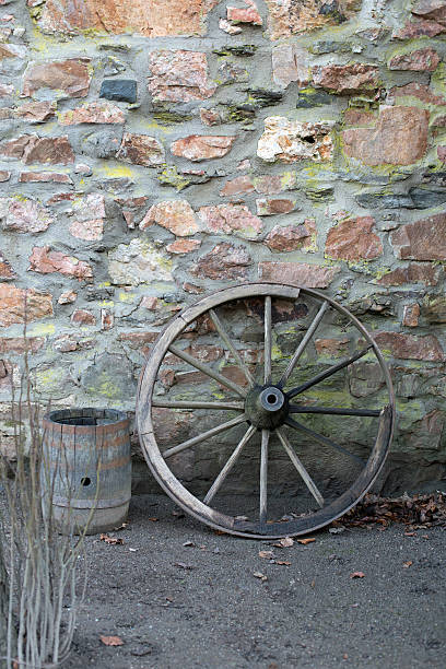 Old wooden wagon wheel and barrel on a stone wall