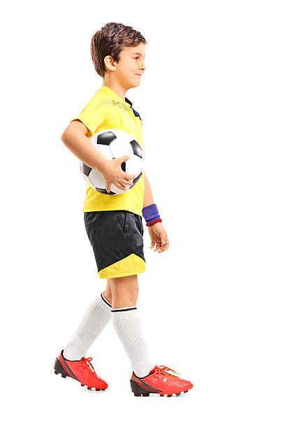 istock Young boy walking and holding a football 508820091