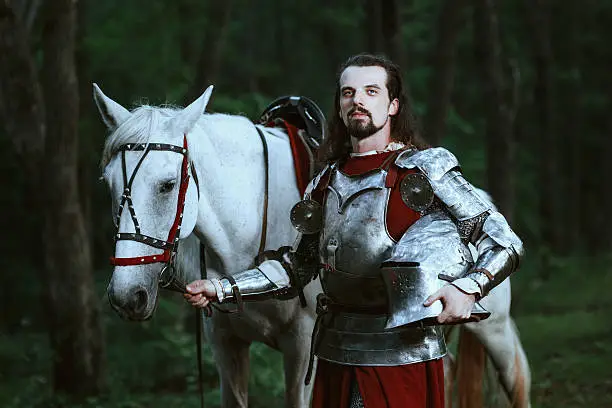 Knight with white horse wolking in the forest