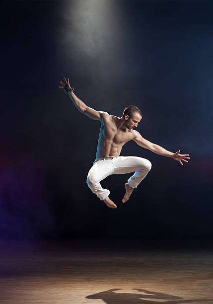Contemporary Dance Young and muscular man performing a contemporary dance pose on a stage. contemporary dance stock pictures, royalty-free photos & images