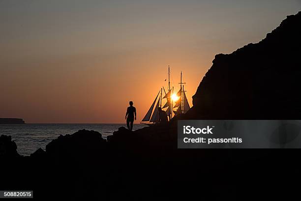 Silhouettes Of A Couple And Sailing Boat At Sunset Stock Photo - Download Image Now - Sailboat, Adult, Aegean Sea
